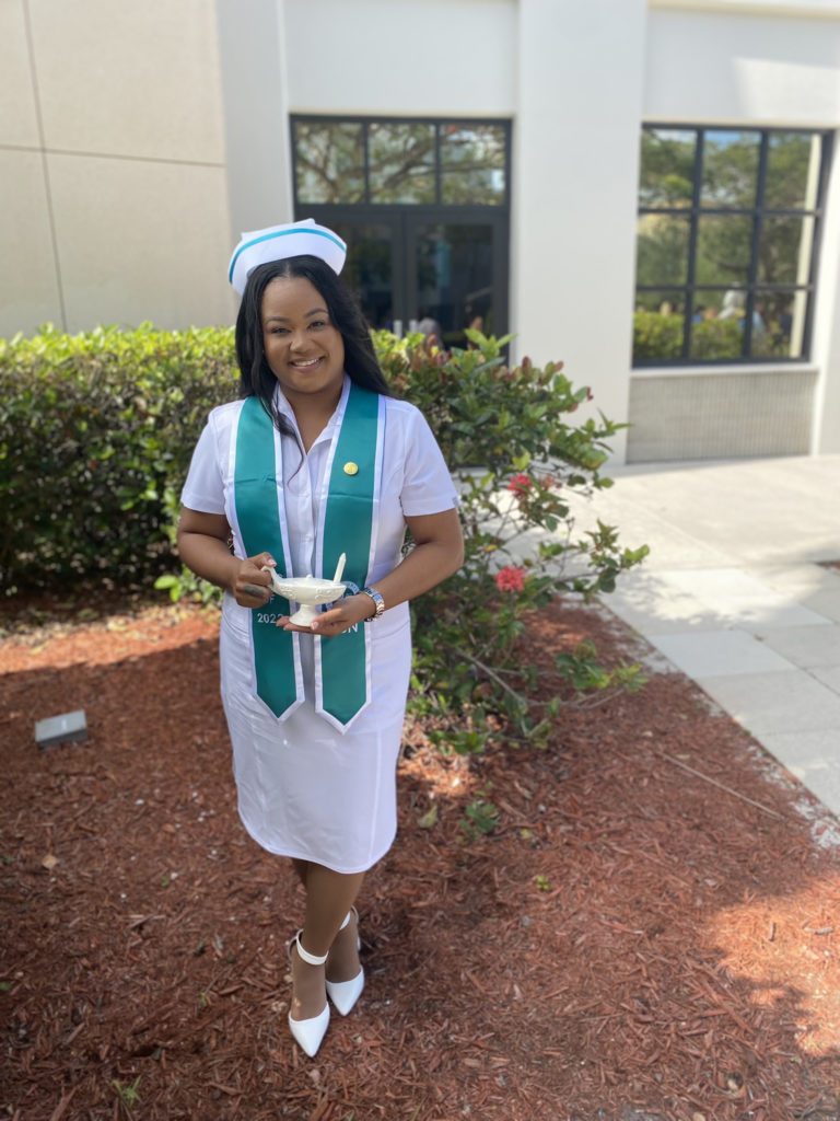 WCU BSN graduate Maisha Gayle West in nurse uniform and graduation sash.